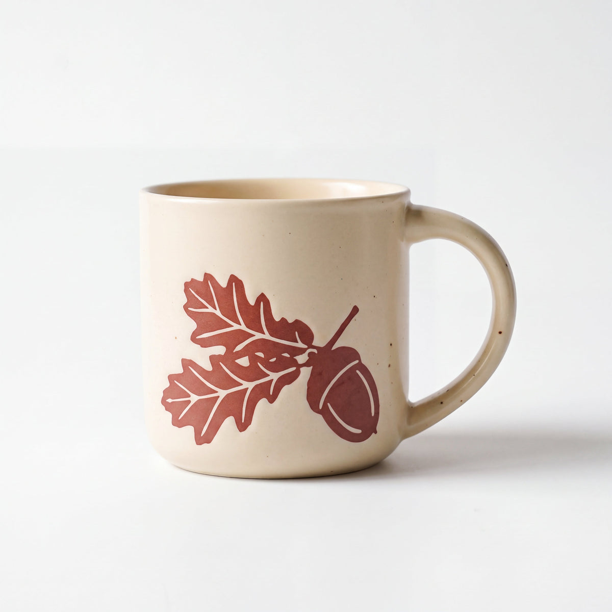 ROOT24STUDIO The Acorn Mug featuring raised terracotta oak leaves and acorn relief on speckled vanilla ceramic