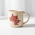 ROOT24STUDIO The Maple Mug featuring raised terracotta maple leaf relief on speckled vanilla ceramic