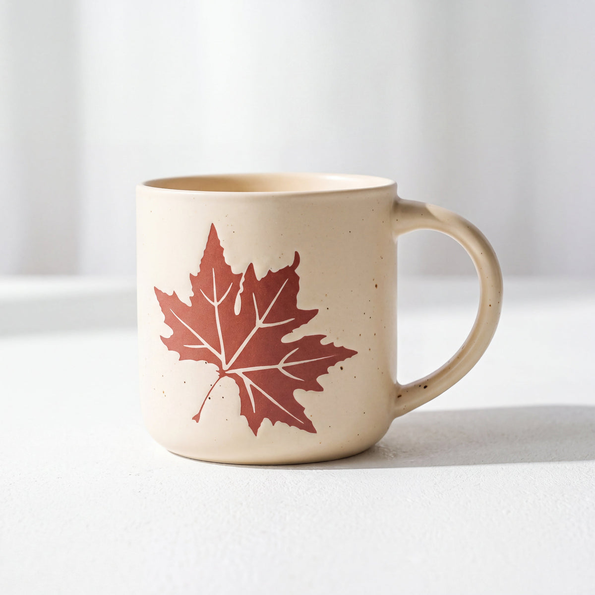 ROOT24STUDIO The Maple Mug featuring raised terracotta maple leaf relief on speckled vanilla ceramic