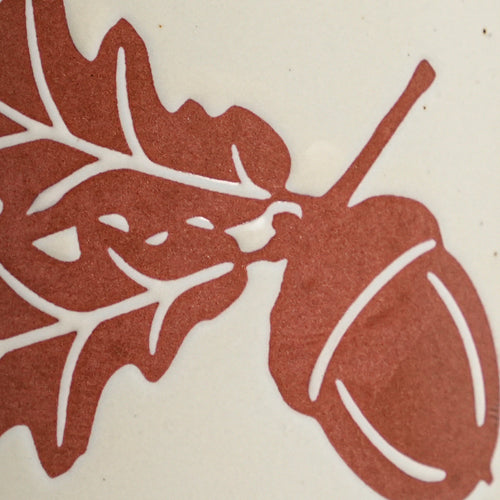 Macro detail of tactile wax-resist oak leaf relief on matte speckled Vanilla Ice glaze