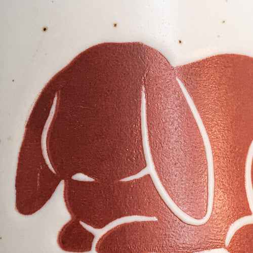 Close-up of the raised sleeping bunny motif showing smooth curved paws and natural ceramic iron speckles