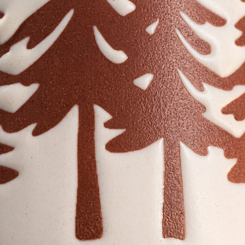 Close-up of pine tree trunks rising from the base showing raw clay texture and natural iron speckles