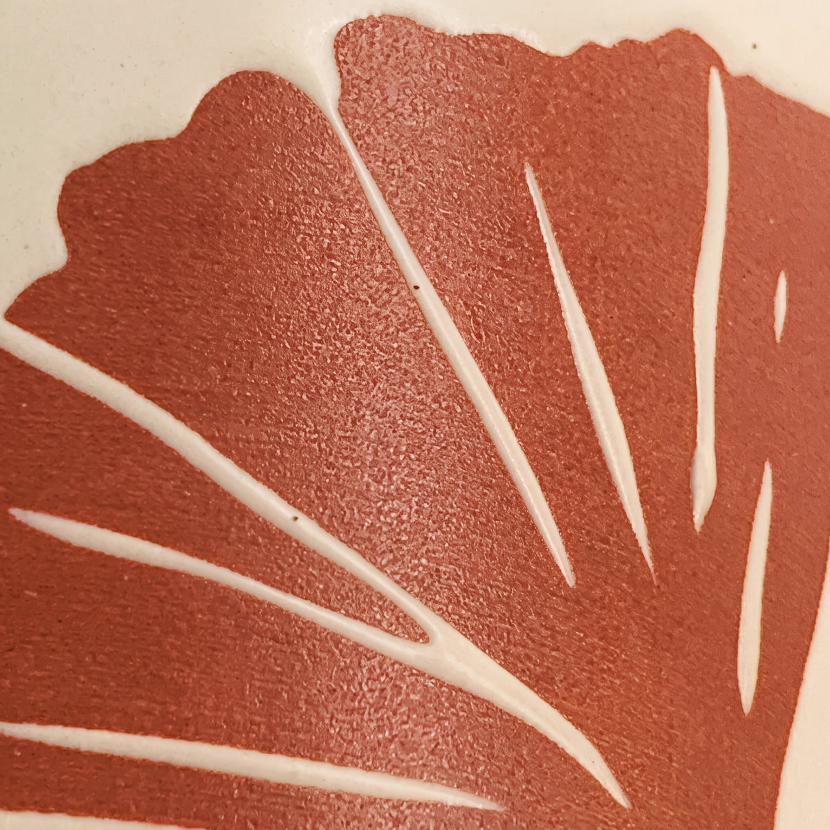 Macro detail of raised ginkgo leaf fan veins showing fine ceramic texture and iron speckles