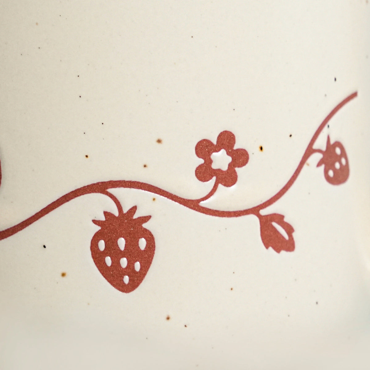 Close-up of hanging terracotta wild strawberry motif showing fine seeds and natural clay speckles