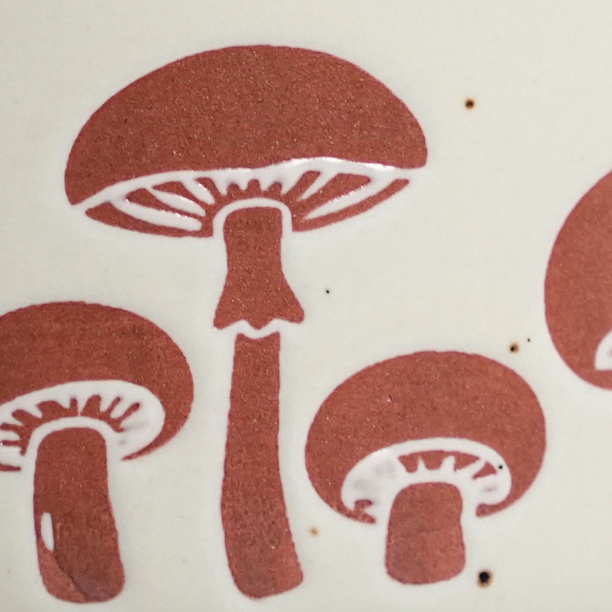 Close-up of tactile wax-resist mushroom relief on speckled Vanilla Ice stoneware glaze