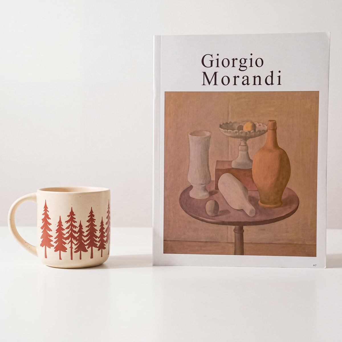 Minimalist styling of The Evergreen stoneware mug beside a Giorgio Morandi art book